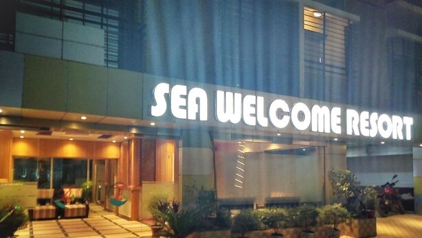 Das äußere Erscheinungsbild des Sea Welcome Resorts mit einem markanten Eingang, Pflanzkübeln und einem mit Fliesen belegten Weg, der zum Eingang führt.