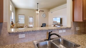 A kitchen with granite countertops, stainless steel sink, ceiling fan, and a clock on the wall. - *Tranquil Living in the City* (Las Cruces)