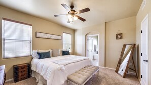 A bedroom with a bed, a bench, a ceiling fan, a dresser, and a window. - *Tranquil Living in the City* (Las Cruces)