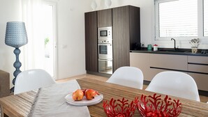 A modern kitchen with dark wood cabinets, a built-in oven, and a window with blinds. - Villa for 6 People in Sicily with private pool at the Sea (Reitani)