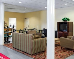 A hotel lobby with a striped sofa, a television, and a dining area with chairs and tables.