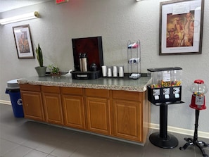 A reception area with a counter, a coffee machine, a water dispenser, a waste bin, and a vending machine.