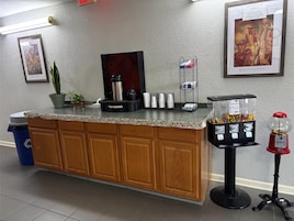 A reception area with a counter, a coffee machine, a water dispenser, a waste bin, and a vending machine.
