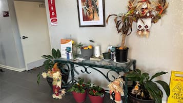 Un'area di accoglienza con una scrivania, piante in vaso, un'opera d'arte incorniciata e un cartello di benvenuto.