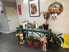 A reception area with a desk, potted plants, a framed artwork, and a welcome sign.