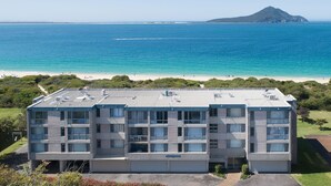 Un hôtel à plusieurs étages, doté d’un toit plat, de grandes fenêtres et d’une enseigne indiquant « Ocean Shores ».