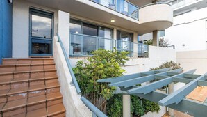 A modern building with a staircase leading to a balcony, surrounded by greenery. - Peninsula Waters, 3/2-4 Soldiers Point Rd - Beautiful Air Conditioned Unit with Pool, Lift & WIFI (Soldiers Point)