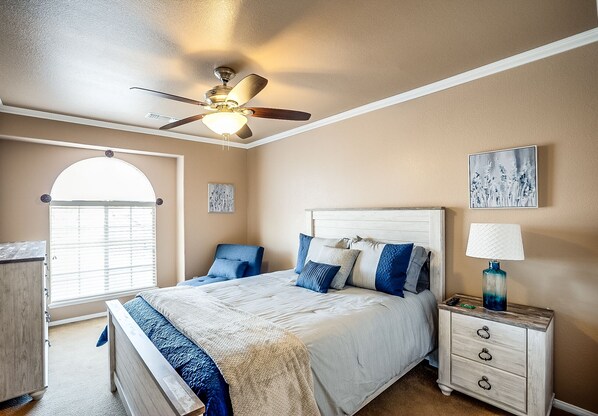 A bedroom with a bed, a nightstand, a ceiling fan, a window, and a door. - Upscale 4 BR Home with RV parking (Henderson)