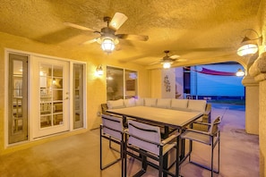An outdoor patio with a dining table and chairs, ceiling fans, and wall-mounted lights. - Upscale 4 BR Home with RV parking (Henderson)