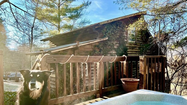 A hot tub on a wooden deck with a wooden fence and a wooden cabin in the background.