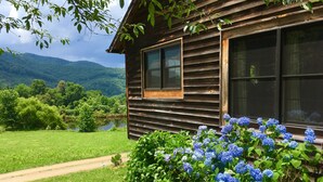 A wooden cabin with a view of a lake and mountains.