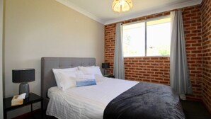 A hotel room with a bed, two bedside tables, a lamp, and a window with curtains.