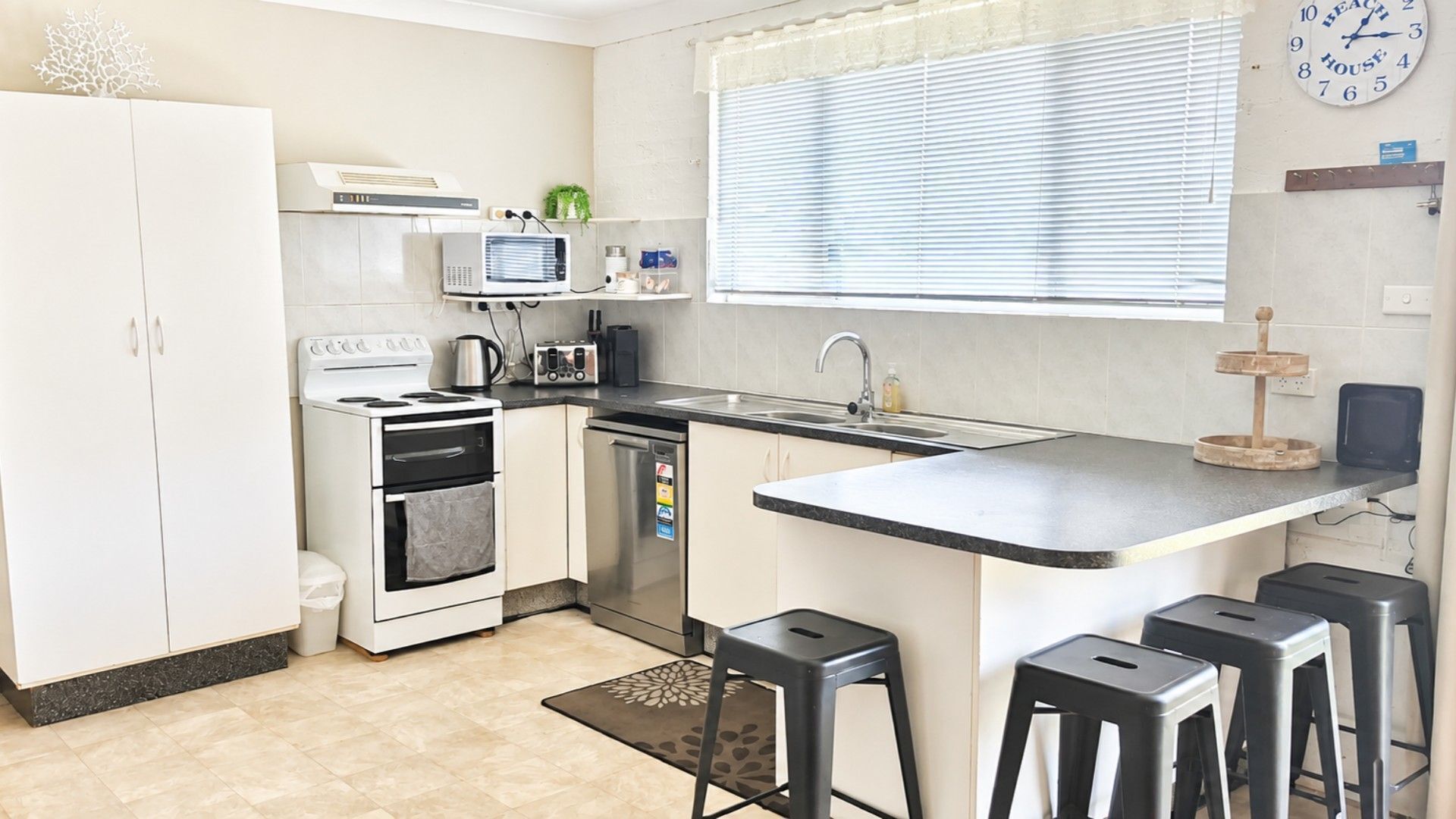 Una cocina compacta con estufa, horno, lavavajillas y una pequeña isla con taburetes.
