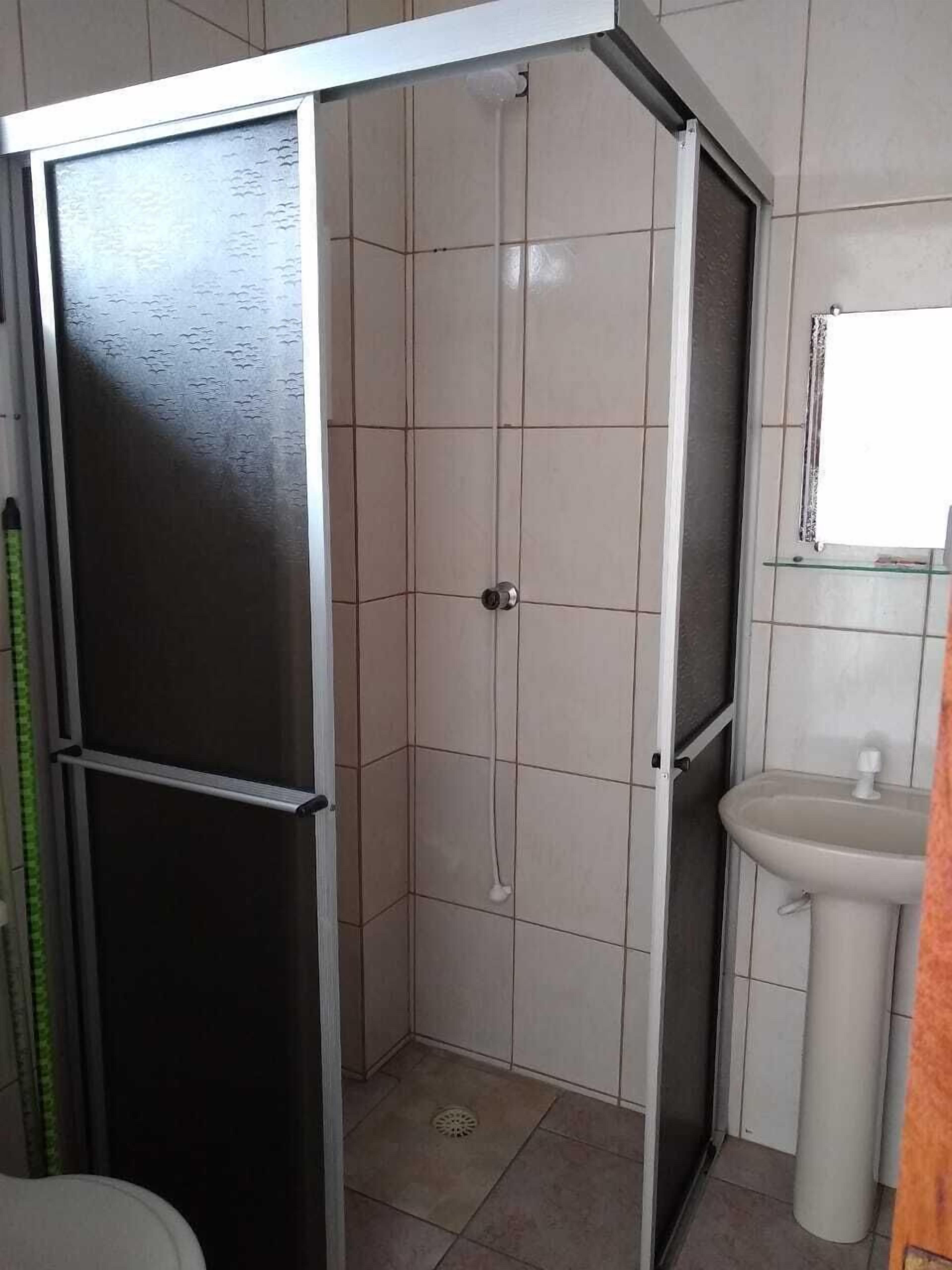 A bathroom with a shower enclosure, a sink, and a toilet.