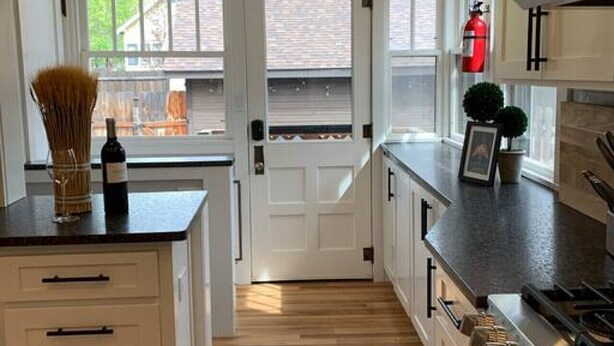 A modern kitchen with white cabinetry, a central island, and a view of Whitman College. - Craftsman on Whitman · Updated Craftsman on Whitman, Close to Everything! (Walla Walla)