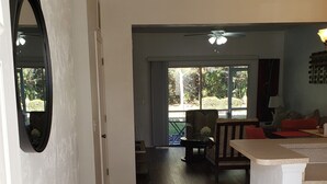 A spacious kitchen with a dining area, a view of the outdoors, and a hallway leading to a balcony.