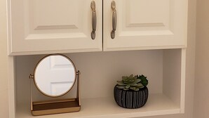 A white cabinet with two doors and a shelf below.