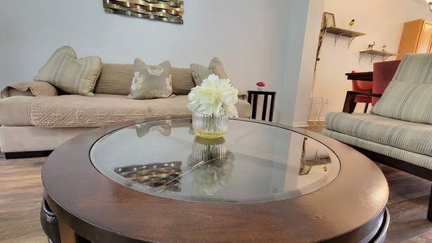 A modern living room with a glass-top coffee table, beige sofa, and a striped armchair.