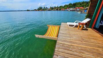 A wooden deck with a lounge chair and a colorful boat.