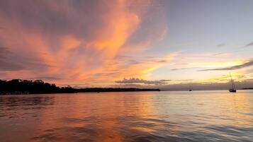 A sunset over a calm body of water with sailboats.