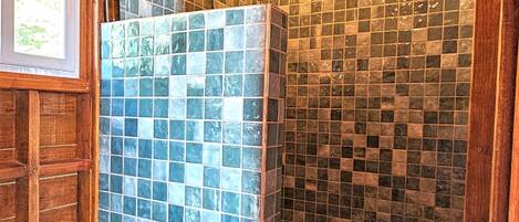 A bathroom with a tiled shower, a toilet, and wooden walls.
