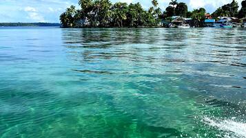 A clear view of a tropical island with a boat creating waves in the turquoise water.