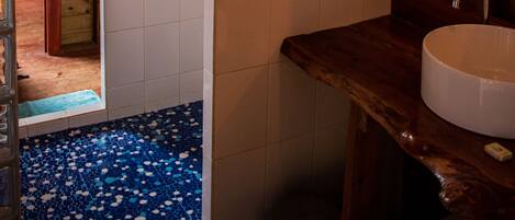 A rustic bathroom with a wooden vanity, a white sink, and a blue-tiled floor.