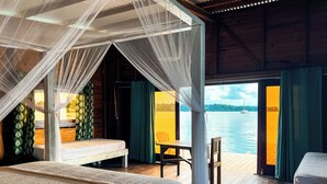 A room with a bed, a chair, and a view of the water.