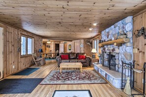 L’intérieur chaleureux d’un chalet avec une cheminée en pierre, des murs en bois et un coin salon confortable.