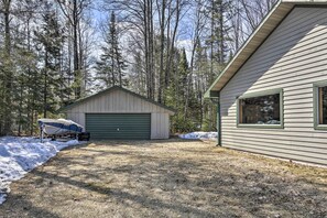 Et hus med garage, en båd på indkørslen og skov i baggrunden.
