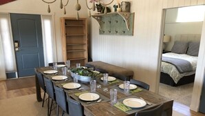 A dining area with a wooden table set for six, surrounded by chairs. A bench is placed along the wall, and a bookshelf is visible to the left. - Georgetown Lake Retreat (Anaconda)