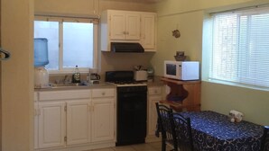 A compact kitchen with white cabinets, a gas stove, a microwave, and a dining table with chairs.