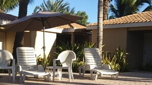 A pool area with clear blue water, white lounge chairs, and palm trees.
