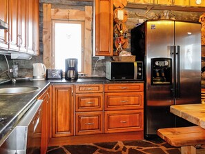 Eine Küche mit Holzschränken, einem Edelstahl-Kühlschrank, einer Mikrowelle und einer Kaffeemaschine.