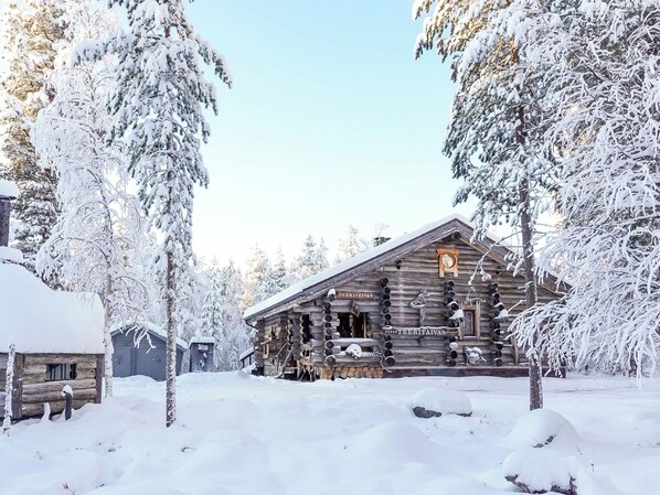 A log cabin surrounded by snow-covered trees.