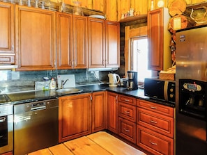 Una cocina con armarios de madera, electrodomésticos de acero inoxidable y una cafetera.