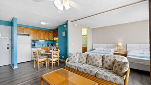 Une chambre d’hôtel compacte comprenant un coin cuisine, un canapé, un lit et un espace repas.