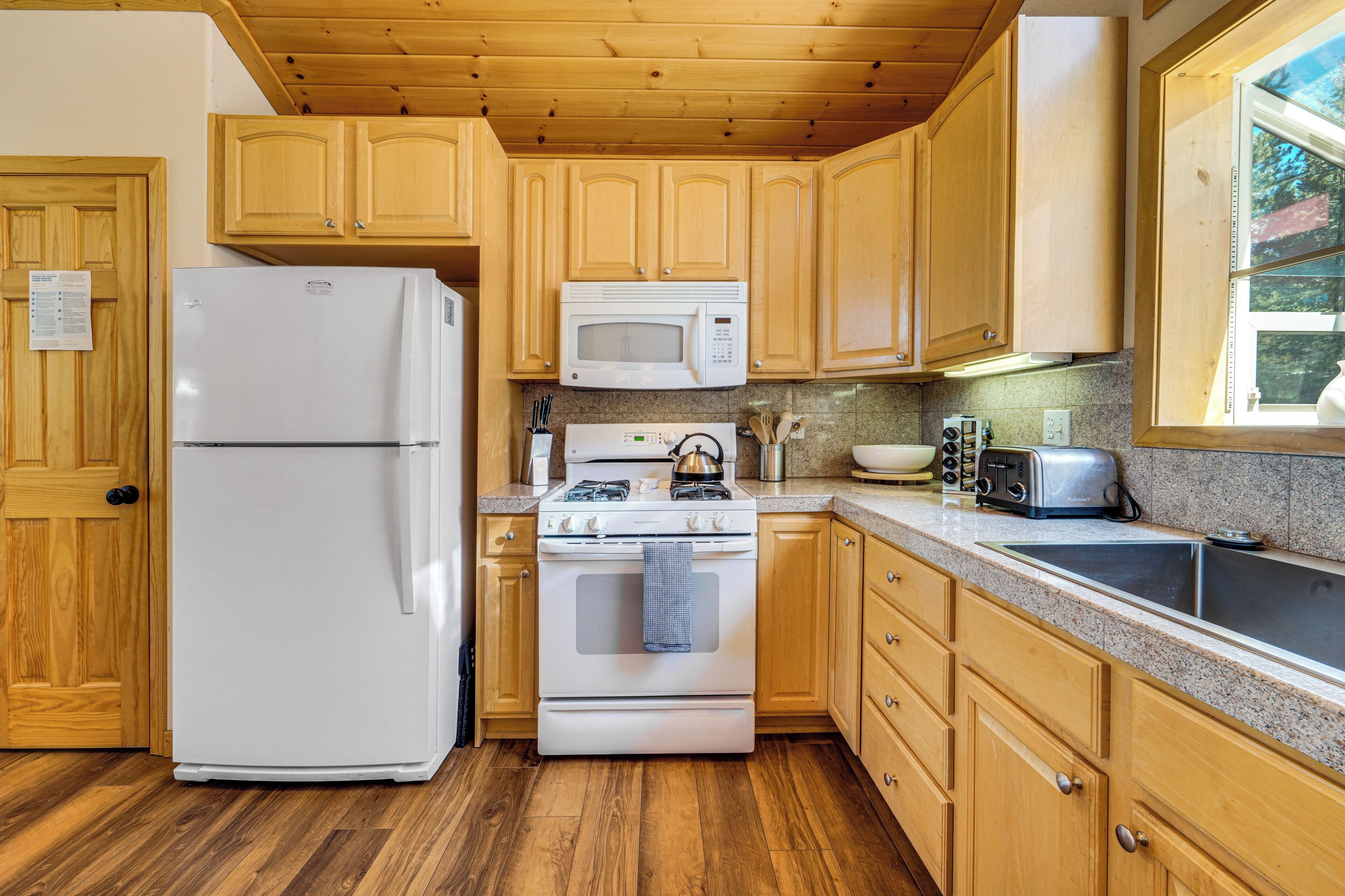 A kitchen with wooden cabinets, a white refrigerator, a microwave, a stove, and a toaster.