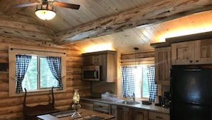 Eine Küchenzeile im Blockhausstil mit Holzwänden, einem Esstisch und einem schwarzen Kühlschrank.
