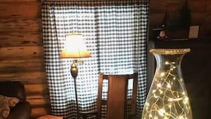 Ein Holzinterieur mit einer Tischlampe, einem Sessel und einer dekorativen Glasvase, die beleuchtet ist.