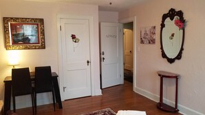 Uma área de refeições com mesa e cadeiras, um quadro na parede e uma porta com placa de identificação.