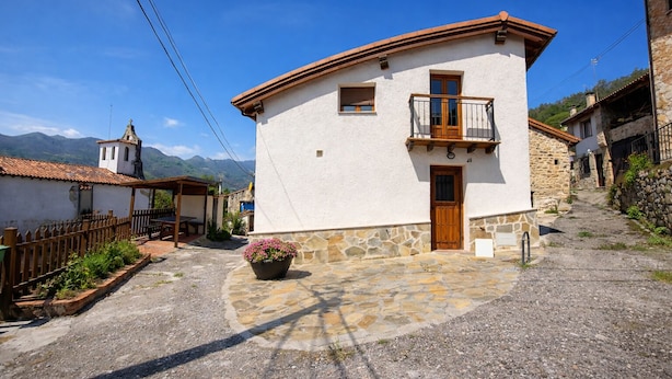 A two-story building with a balcony, a stone foundation, and a small garden with pink flowers. - La Casina de Marina de Tresgrandas (Llanes) (Tresgrandas)