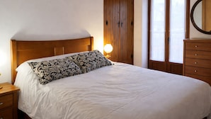 A neatly made bed with a patterned pillow, a bedside lamp, and a wooden wardrobe. - La Casina de Marina de Tresgrandas (Llanes) (Tresgrandas)
