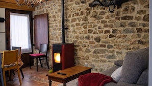 A cozy living room with a stone wall, a wooden table, a red blanket, and a sofa. - La Casina de Marina de Tresgrandas (Llanes) (Tresgrandas)