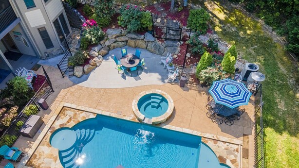 Een zwembad op het dak met een jacuzzi, ligbedden en een eettafel.