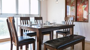 Un coin repas avec une table en bois dressée pour six personnes, entourée de chaises dotées d’assises rembourrées.