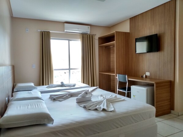A hotel room with a bed, a desk, a chair, and a TV.