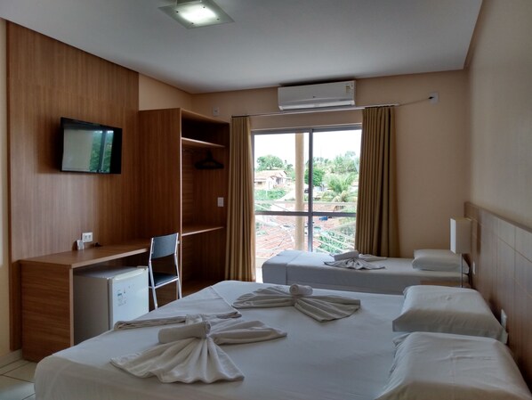 A hotel room with a bed, two bedside tables, a desk, a chair, a TV, and a window with curtains. - Planeta Hotel (Colinas do Sul)