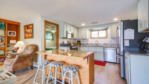 Una cocina con una isla de madera, taburetes de bar y un refrigerador.