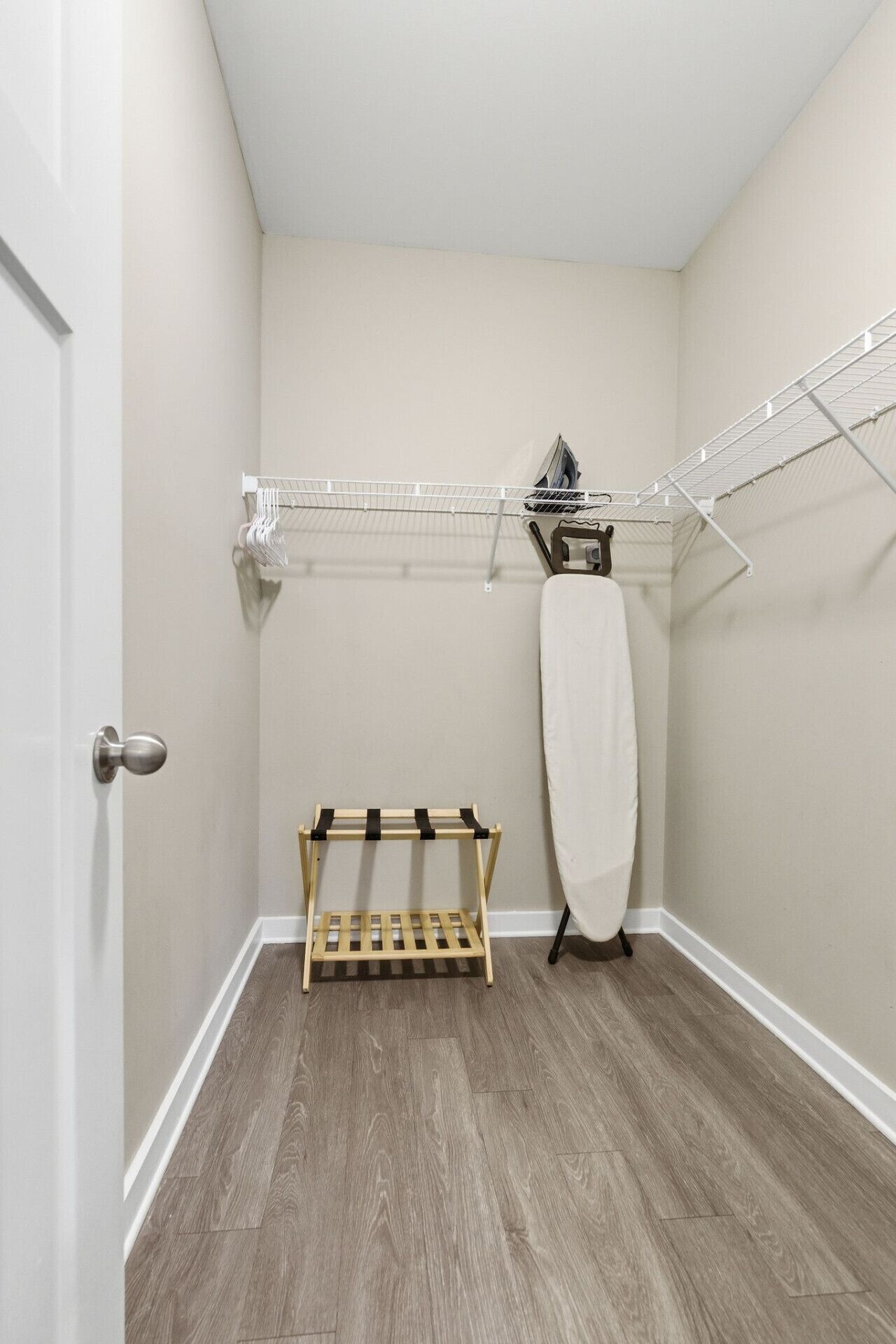 A laundry room with a wooden drying rack, a hanging clothes rack, and a door.